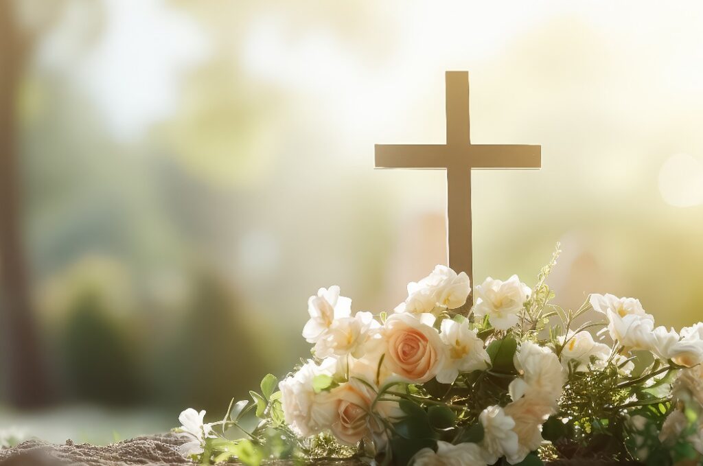Ein Friedhof mit einem Kreuz und einem Sarg, auf dem Blumen liegen