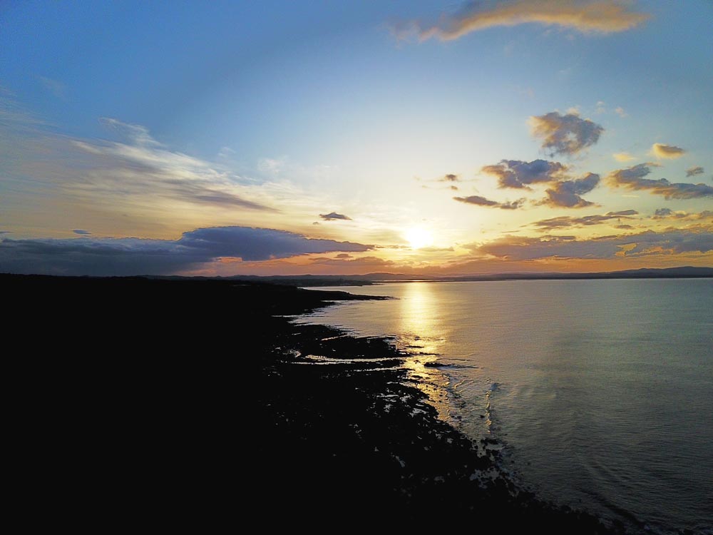 Sonnenuntergang über ruhigem Meer mit reflektierendem Licht und teilweise bewölktem Himmel